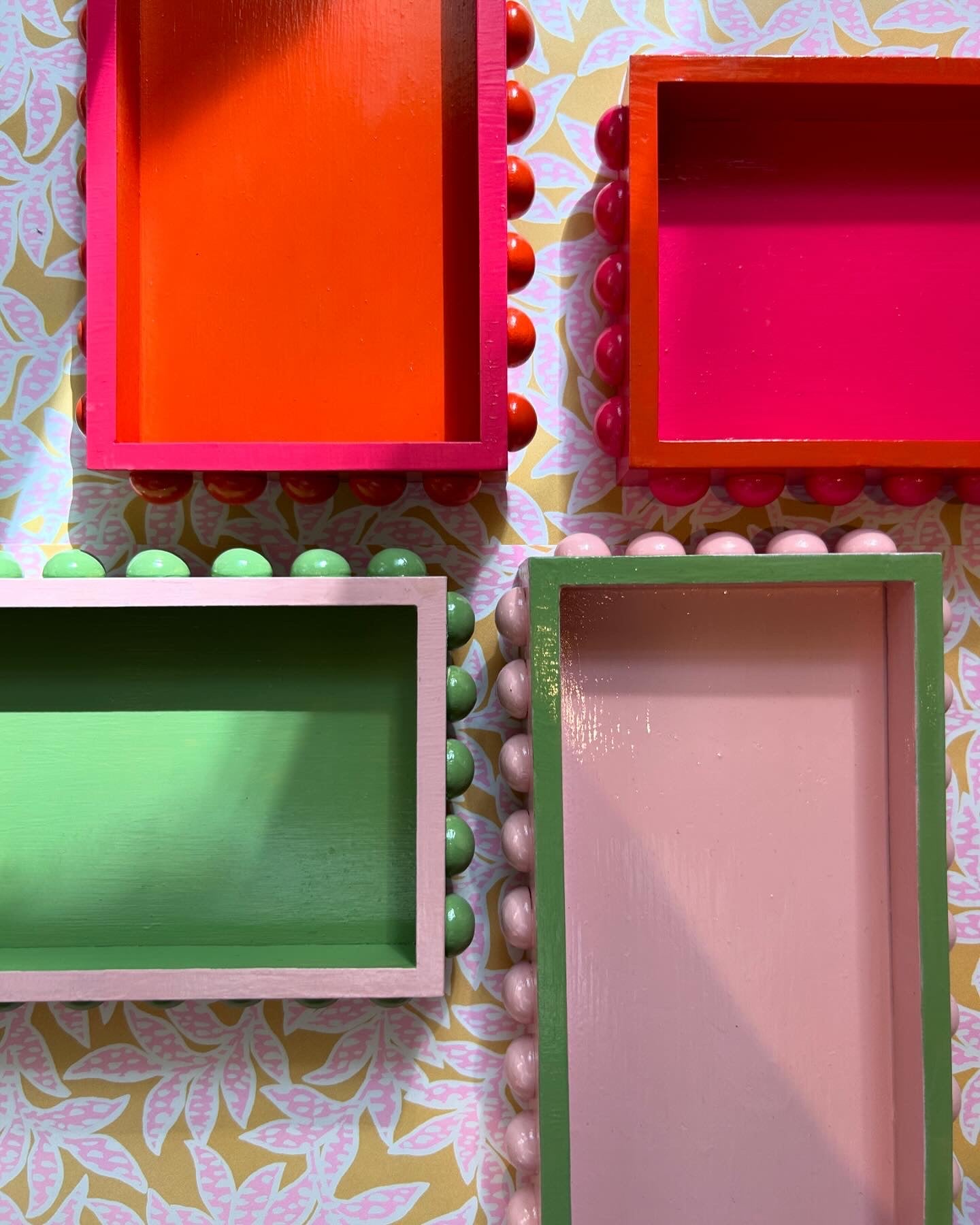 Hand painted bobbin decorative trays in pink, orange and green.