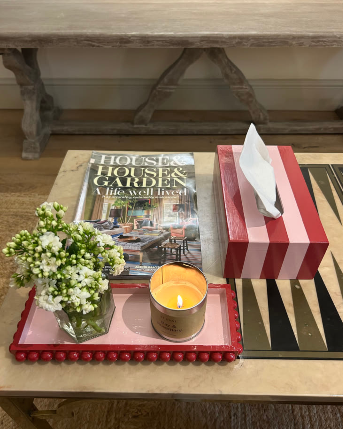 Hand-painted red and pink striped tissue box cover styled on a bedside table with fresh flowers and colourful home accessories.