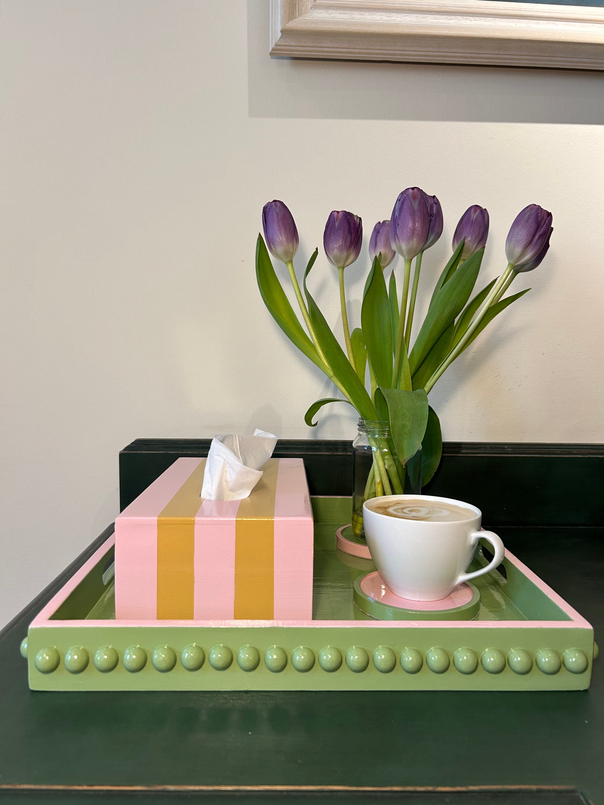 A hand painted square decorative coffee table tray with a green bobbin style pattern and pink edge, gloss finish. 