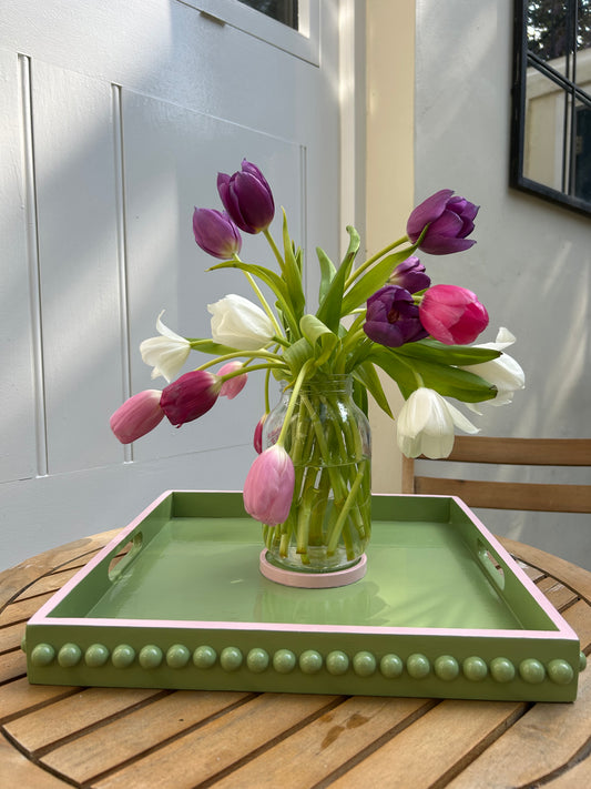 A hand painted square decorative coffee table tray with a green bobbin style pattern and pink edge, gloss finish. 
