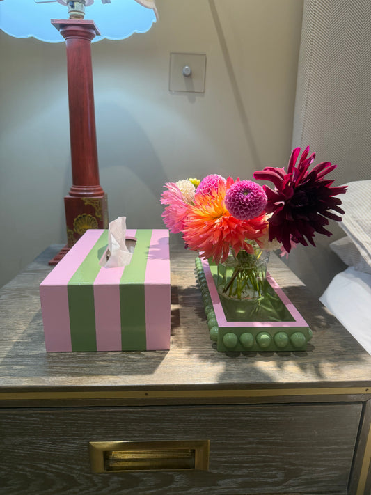 Hand-painted green bobbin style decorative tray with a light pink edge styled on a coffee table with candles, flowers and colourful home accessories.