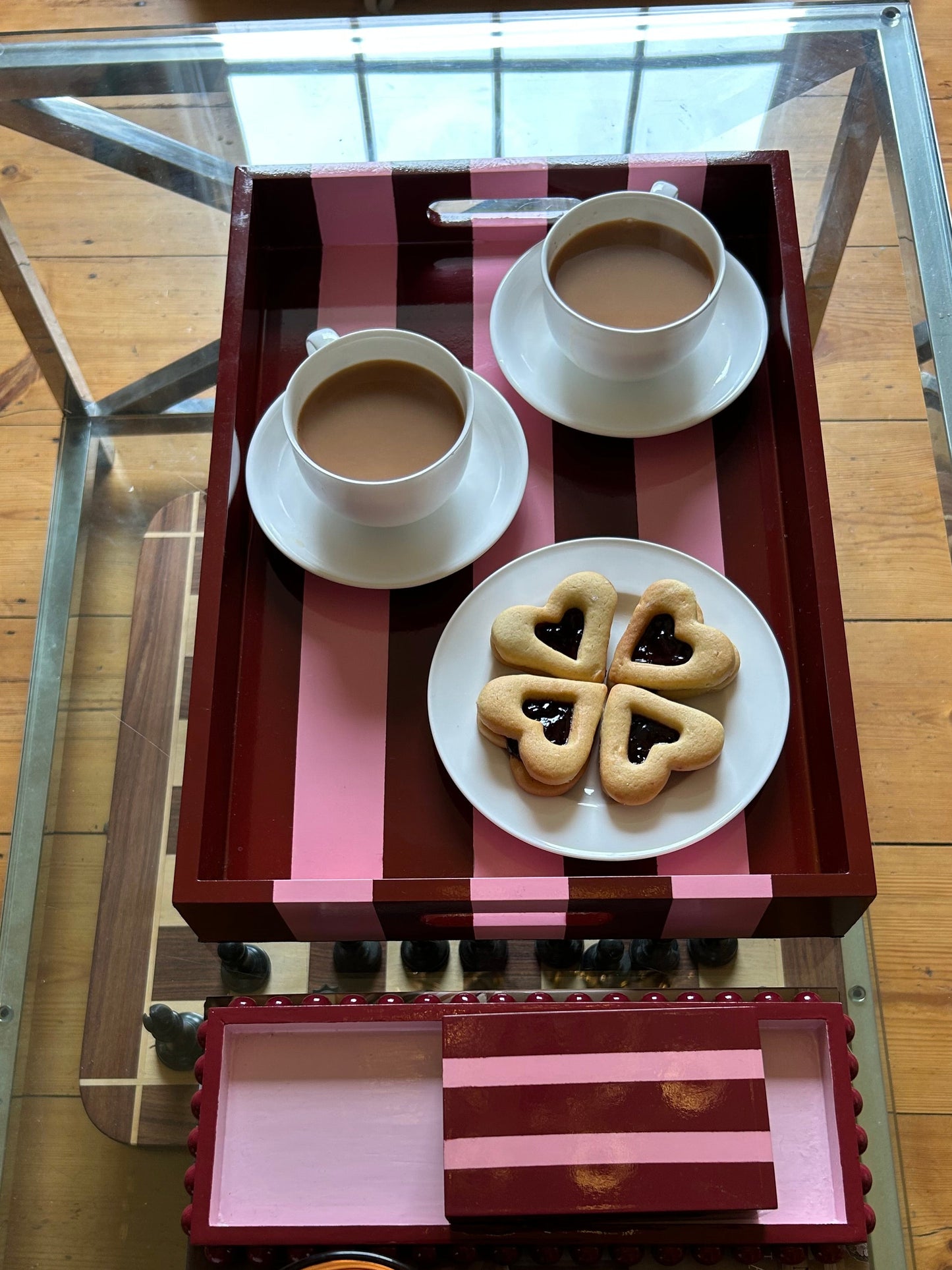 Table setting with cookies, cups, and a candle on a glass table.
