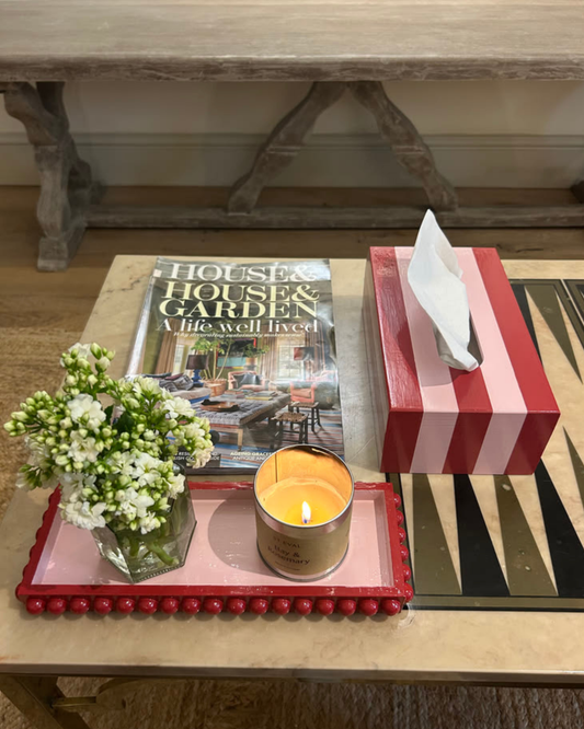 Hand-painted red and pink striped tissue box cover styled on a bedside table with fresh flowers and colourful home accessories.